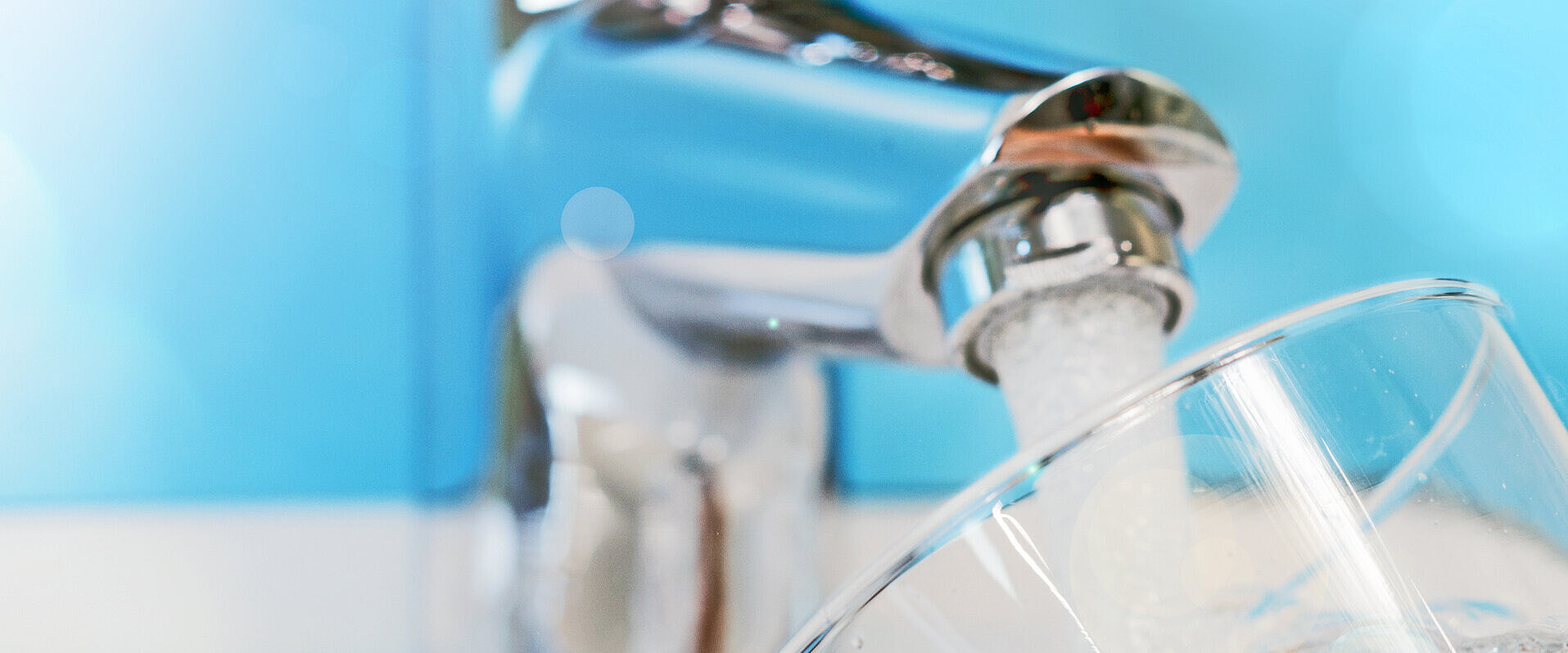 Glas wird am Wasserhahn befüllt.