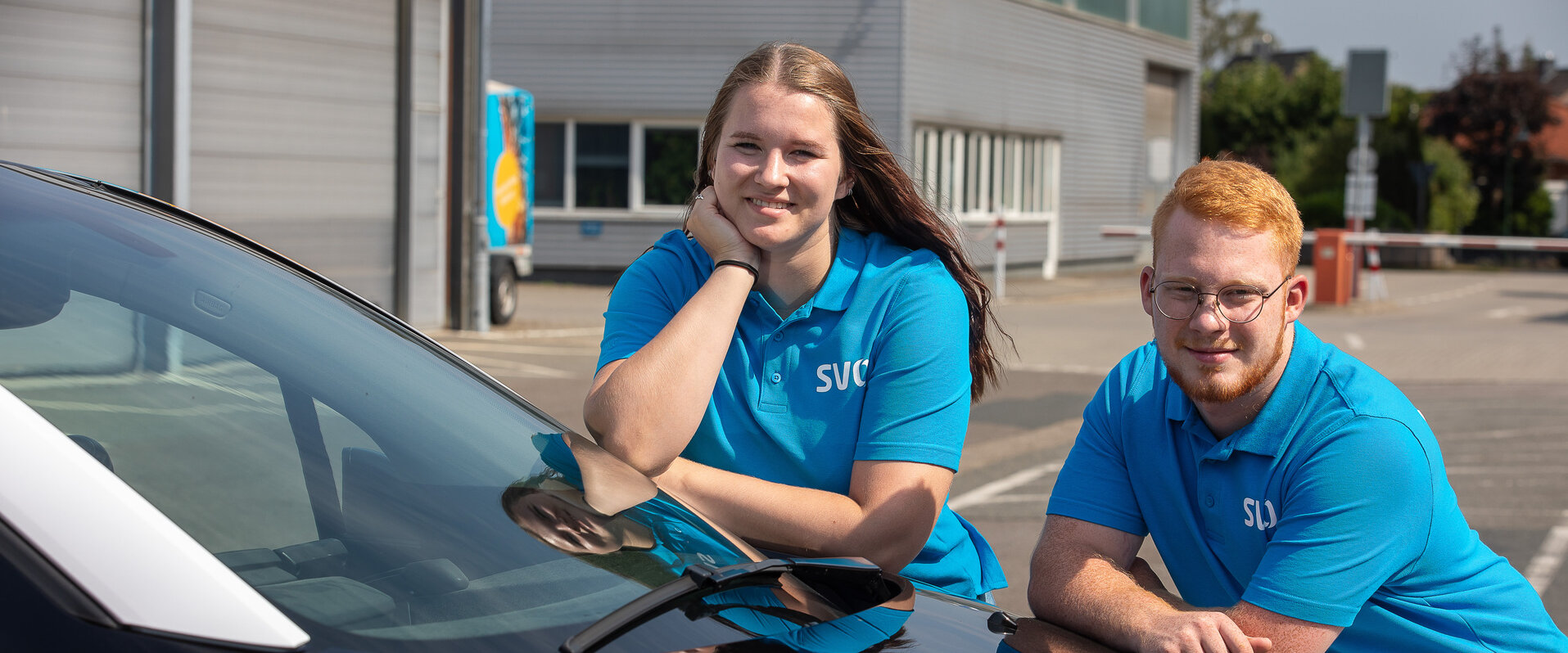 SVO Mitarbeiter mit E-Auto Zwei SVO Mitarbeitende stützen sich auf einem Elektroauto ab und schauen in die Kamera.